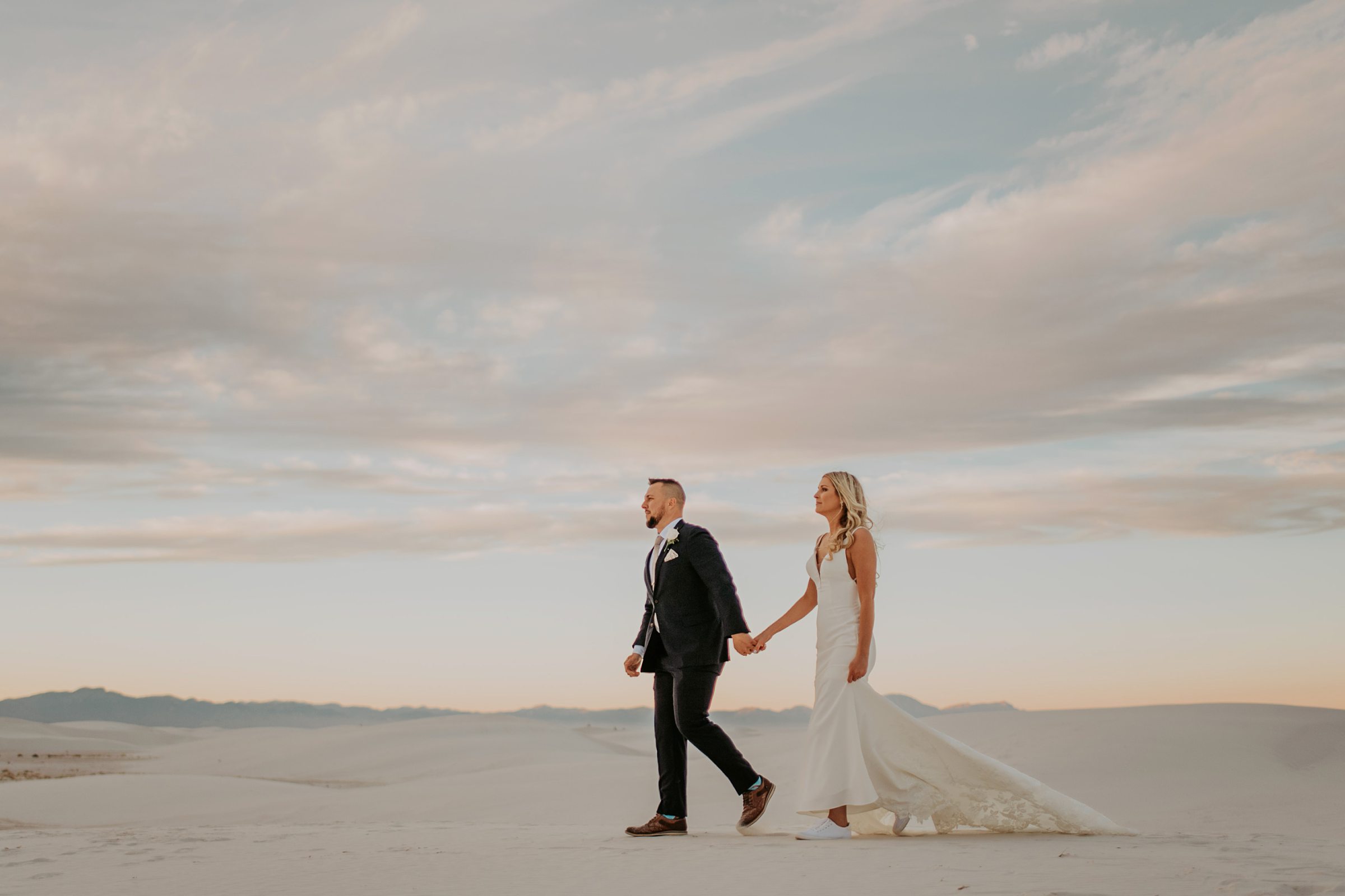 bride and groom walking along the dunes in White Sands National Park after their elopement